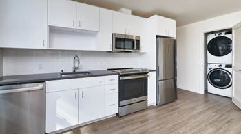 A modern kitchen with white cabinets and stainless steel appliances.